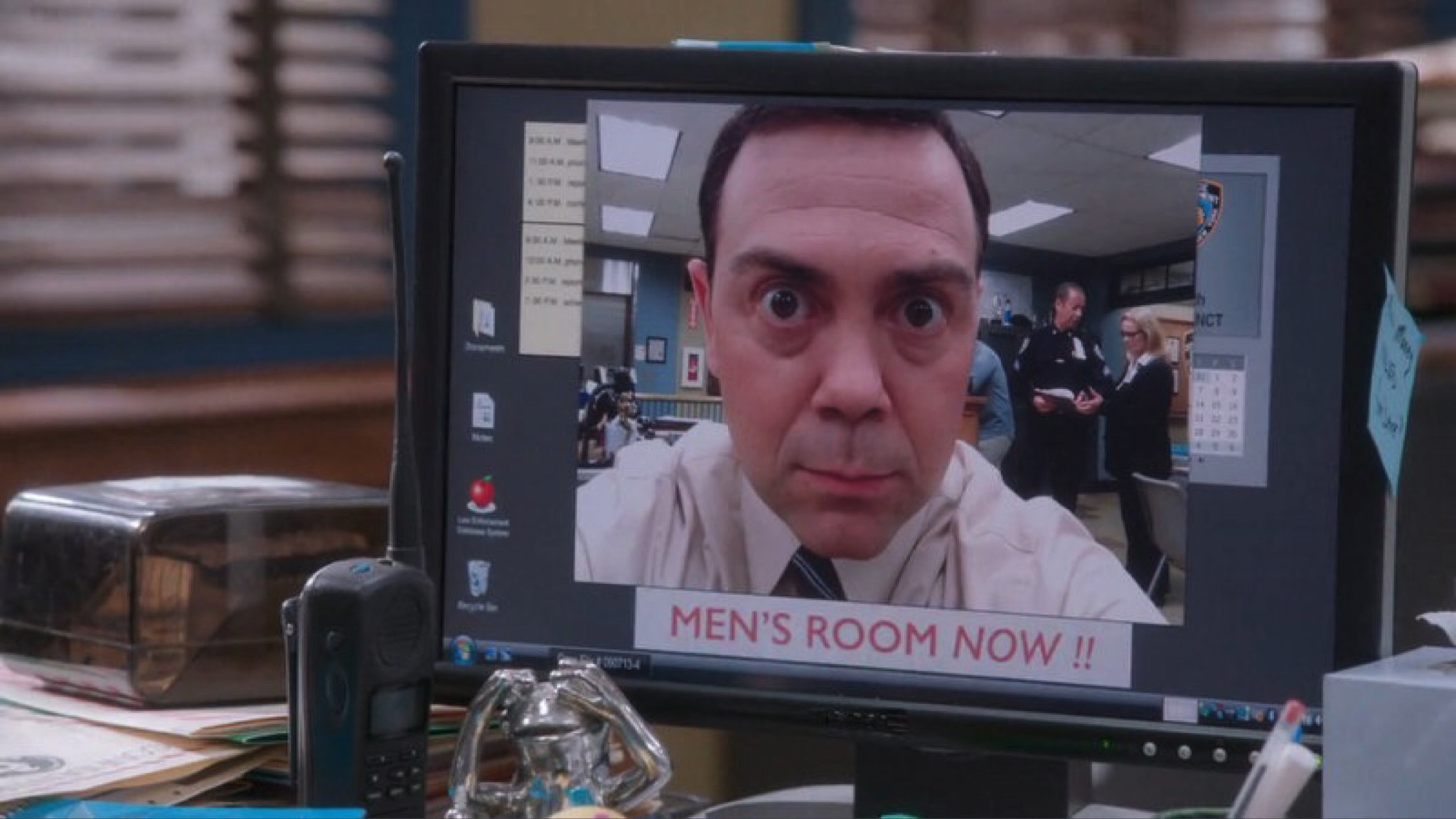 Charles Boyle, a charcter from the TV show Brooklyn 99, on a computer screen,
      with the caption 'men's room, now'